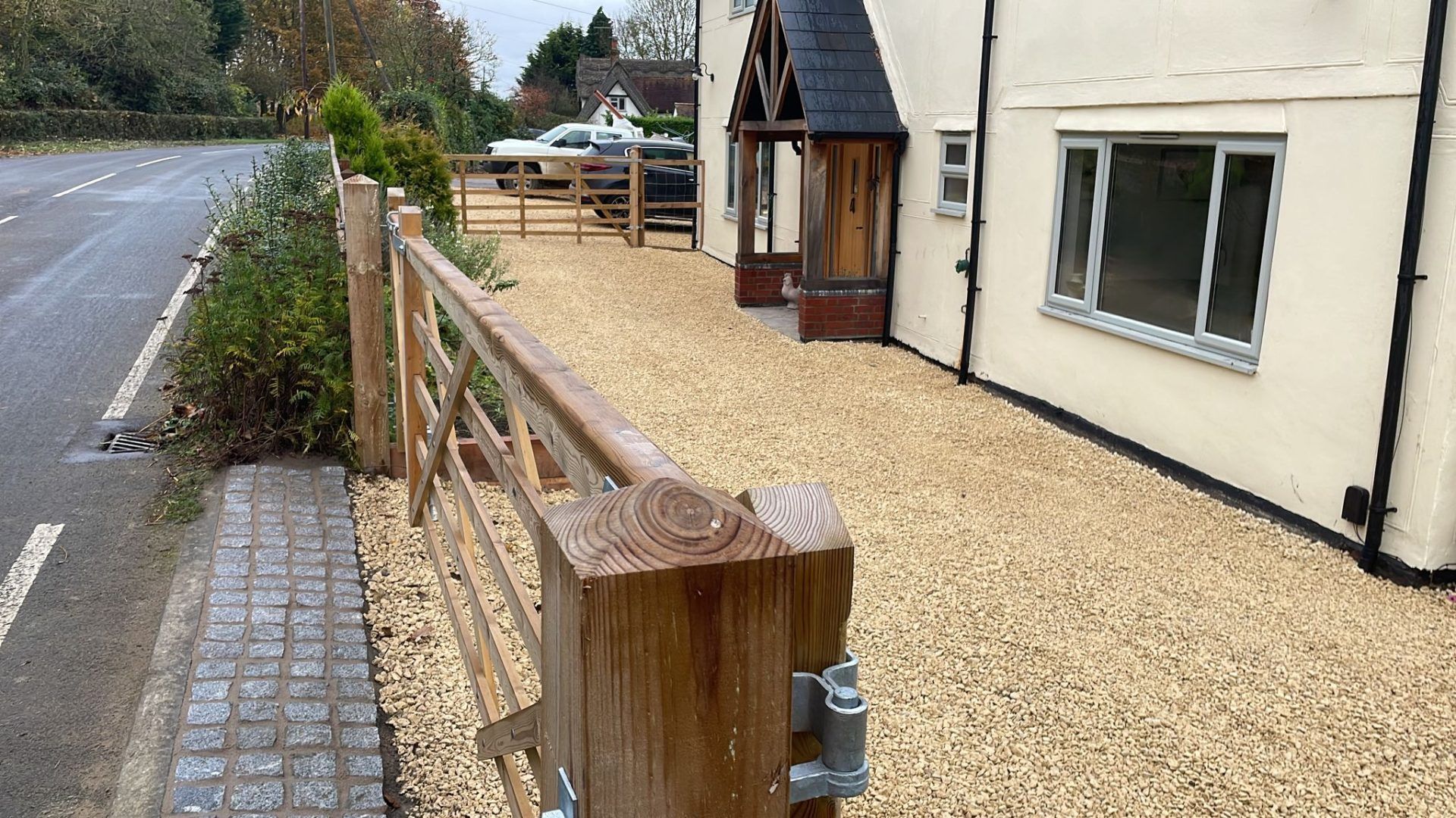 Cream colour house with shingle driveway and wooden 5 bar gate.