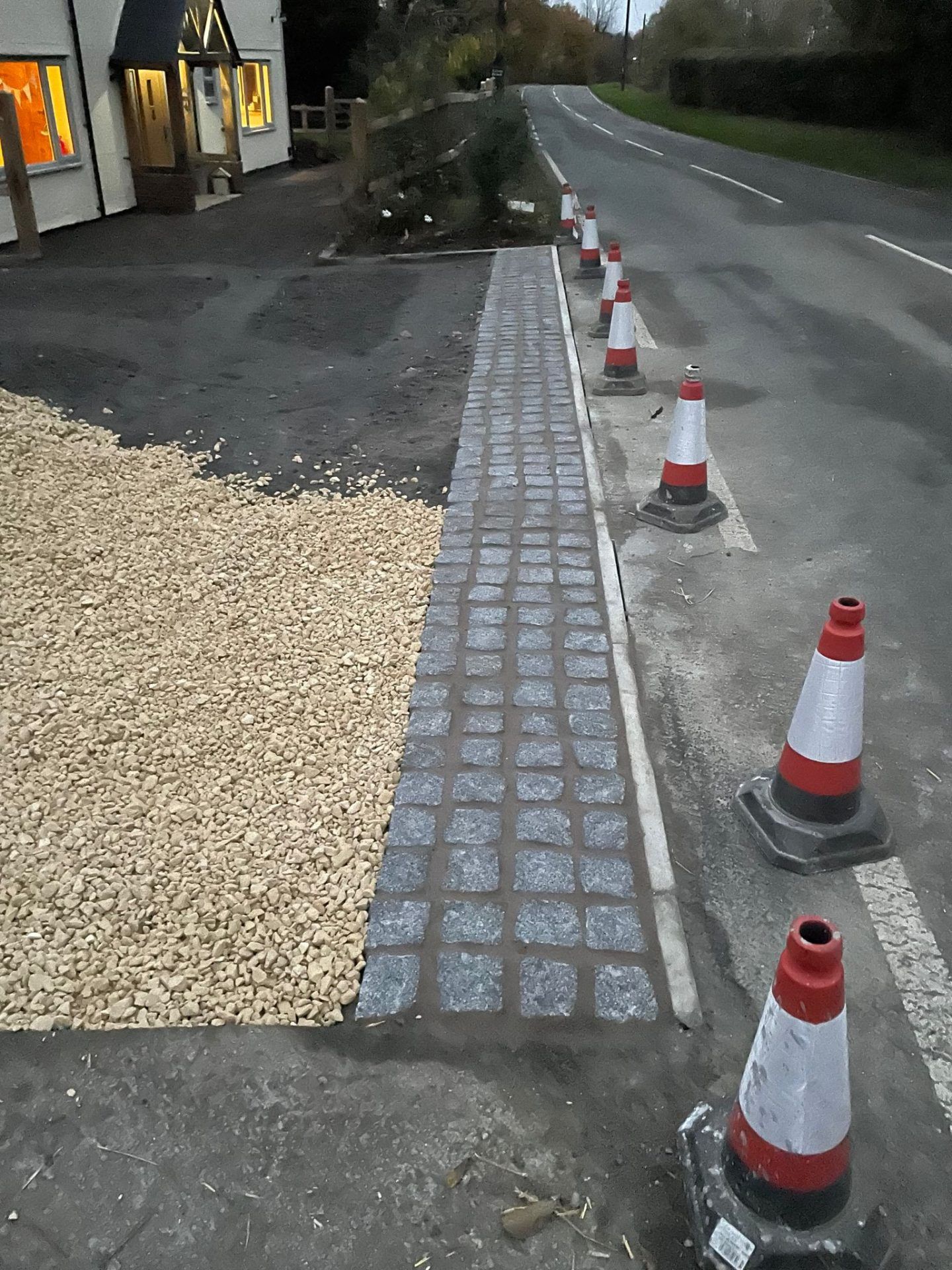 Newly laid block paving edging with traffic cones shielding from road.