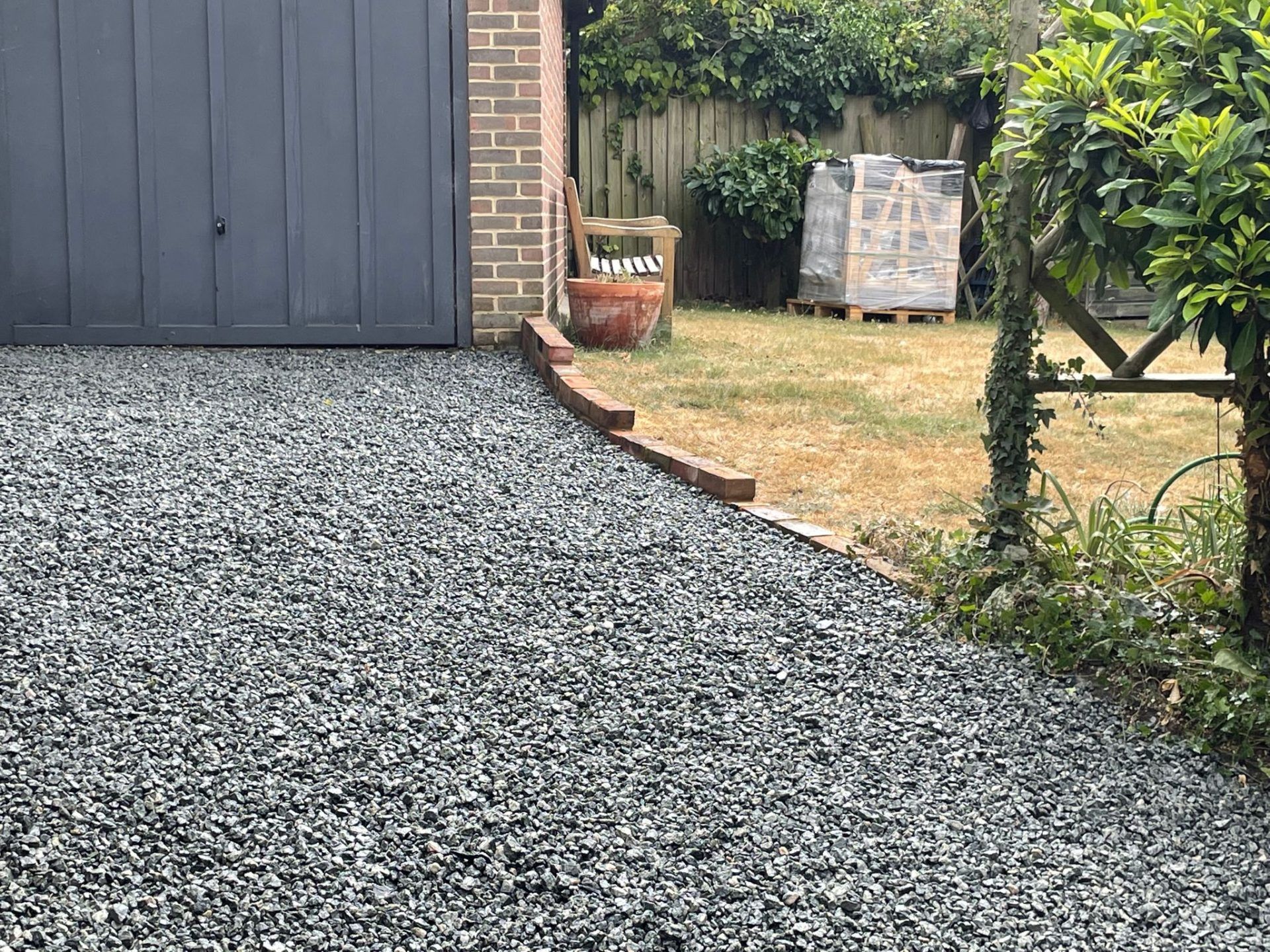 Newly laid chippings in front of garage with view of brick edged lawn beside.