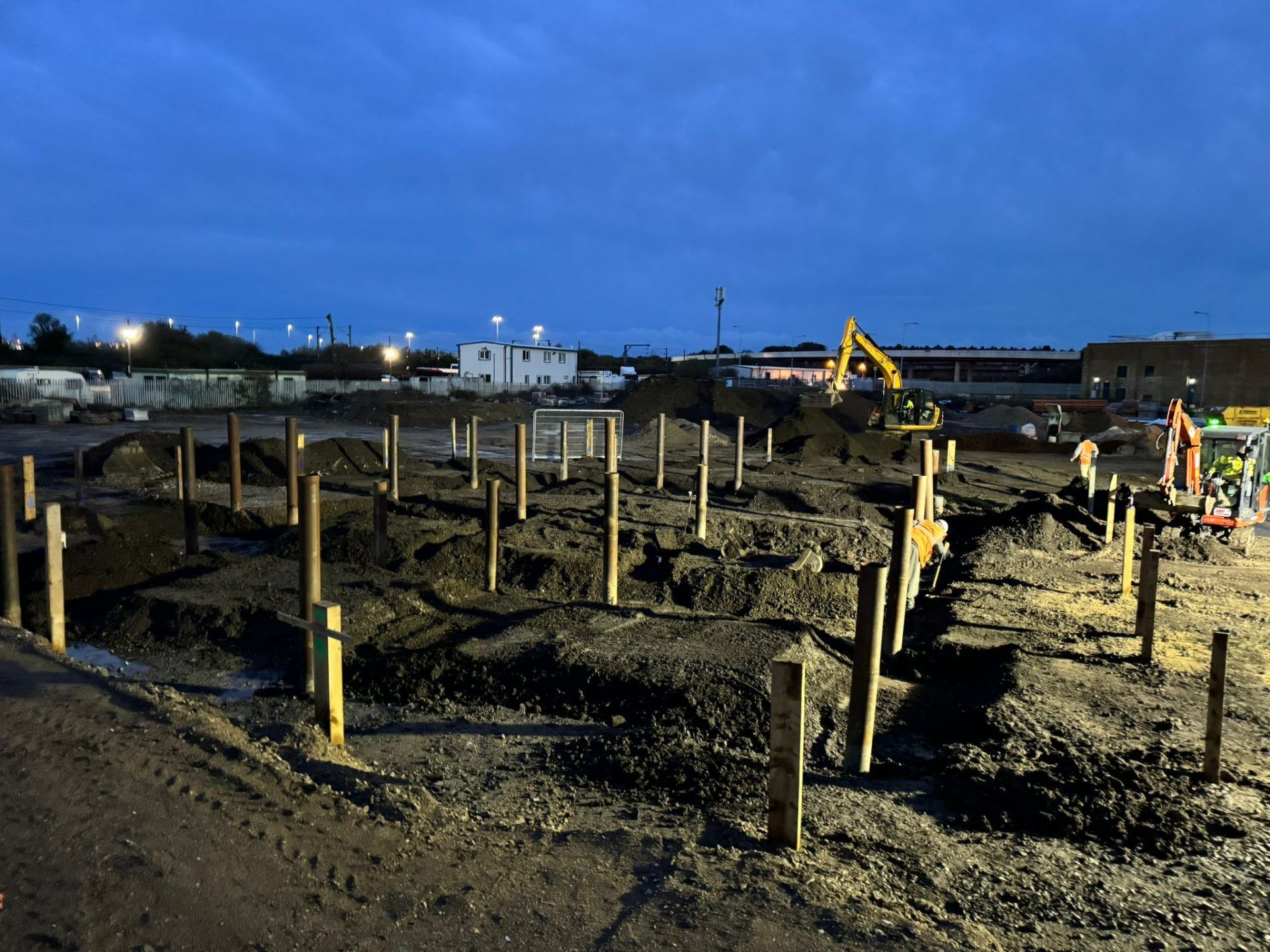 Floodlit view of building site with mechanical diggers.