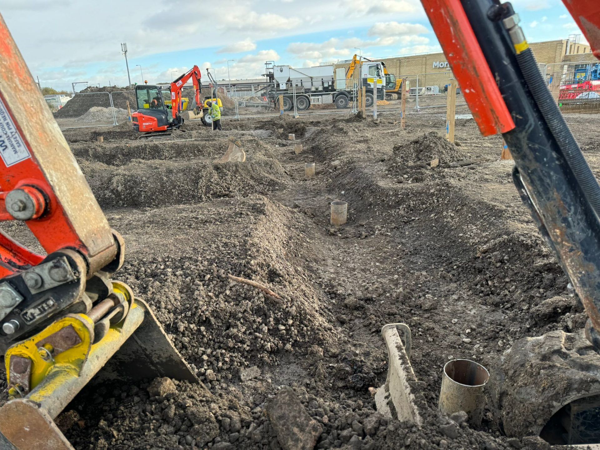 Close shot of trench on building site framed by machinery.